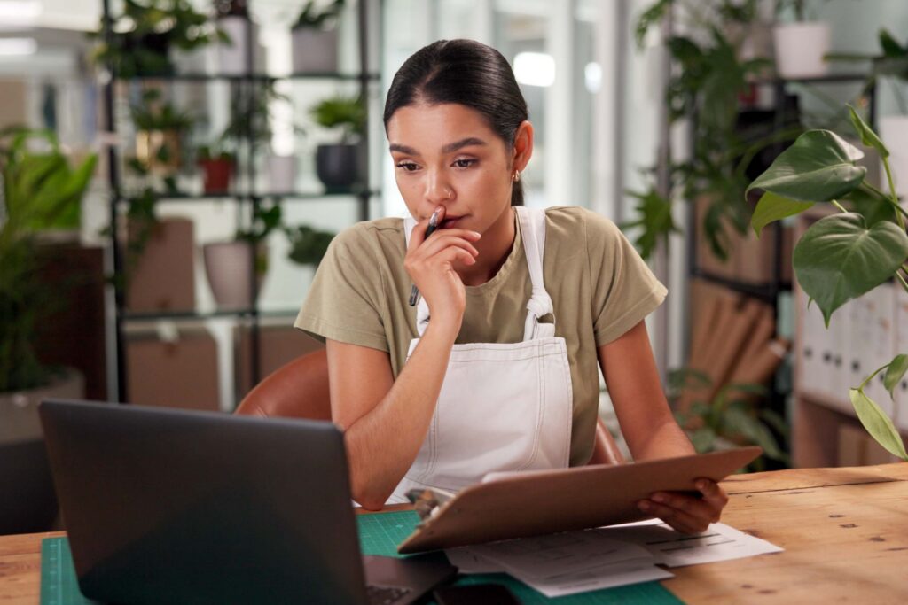 Person reviewing documents while working at a desk with a laptop