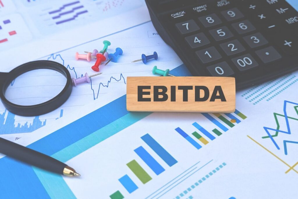 EBITDA displayed alongside a calculator, financial charts, graphs, and office supplies used for financial analysis.