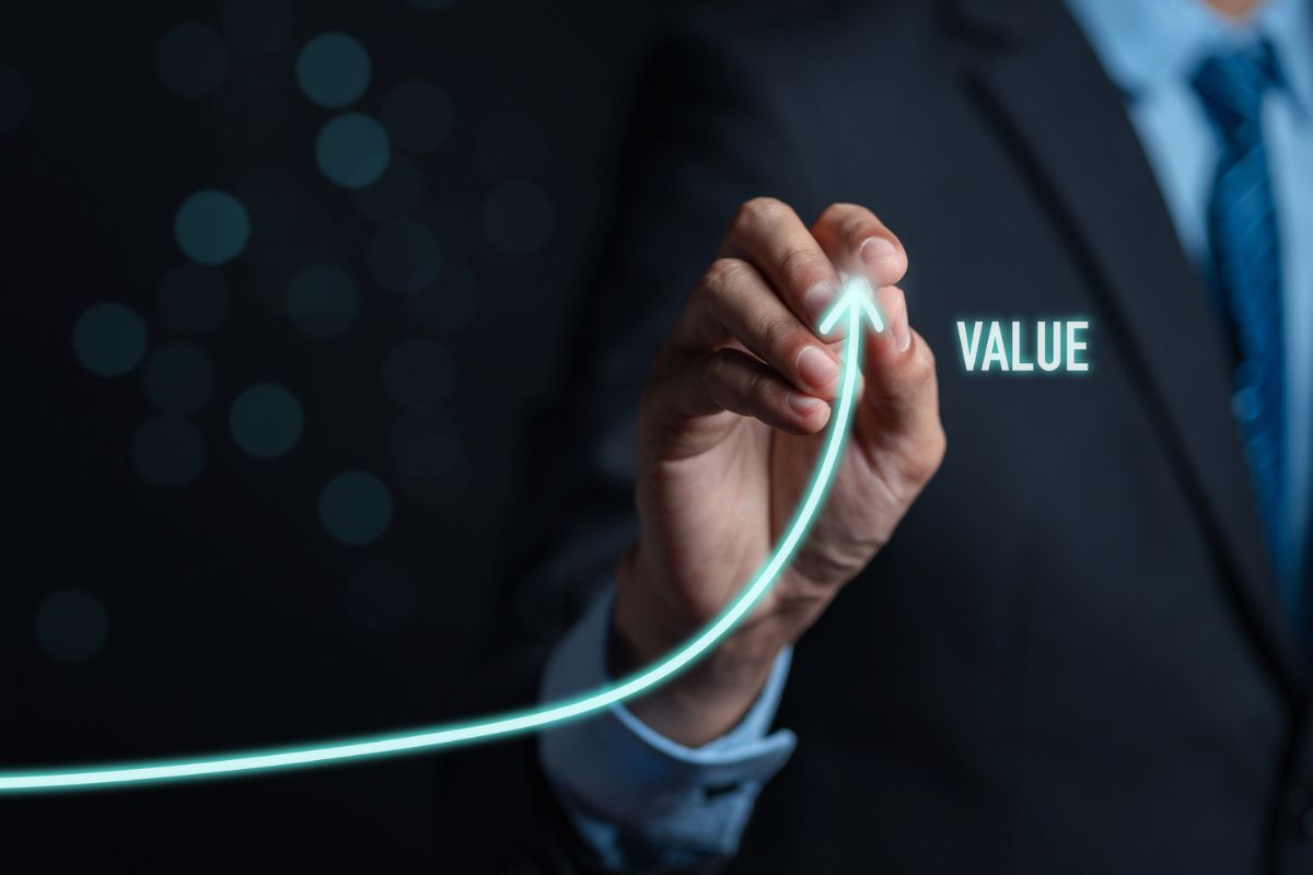 Business professional illustrating an upward growth curve next to the word ‘Value,’ representing increasing business value and performance.