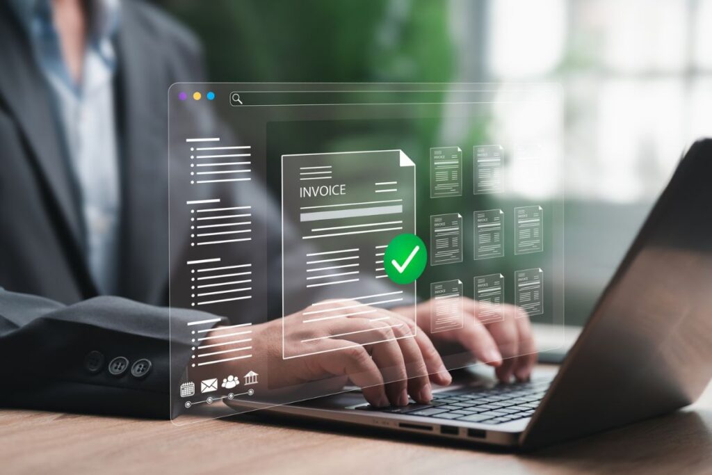 Business professional using a laptop with a digital invoice management interface and approval checkmark displayed on screen