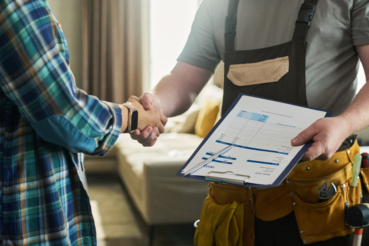 Home service professionals shaking hands over business paperwork.